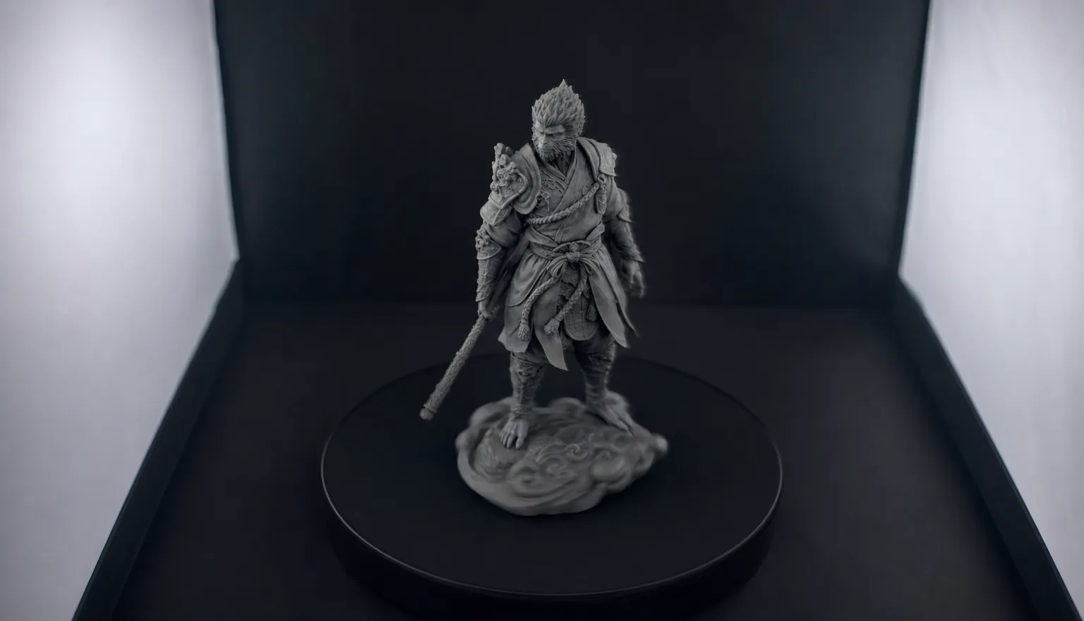 A grey sculpted warrior figure rotating on a matte black turntable inside a photo light tent
