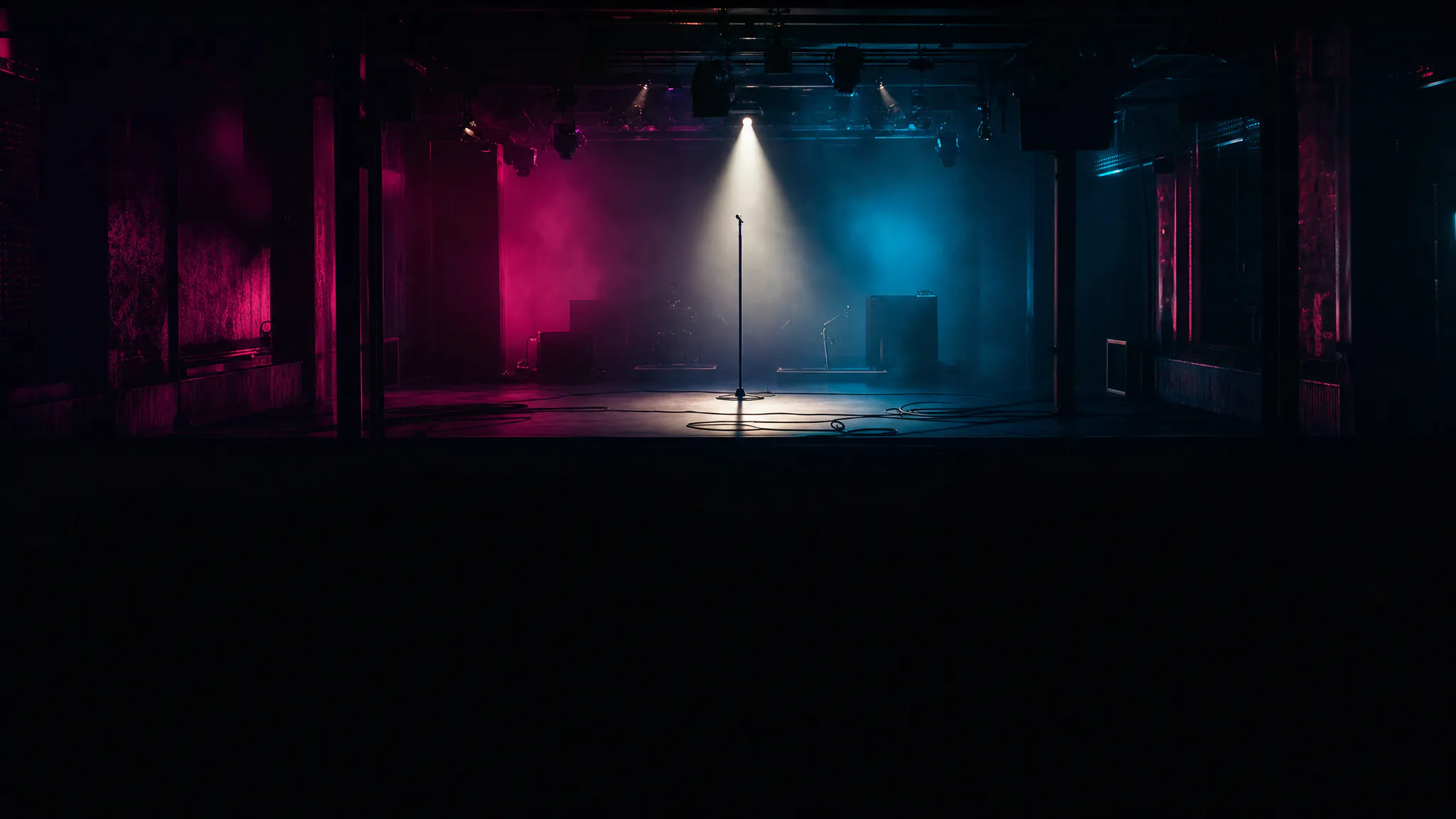 AI music video generator — an empty stage with one microphone in a hard beam, magenta and cyan haze behind